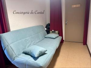 a couch in a room with two pillows on it at Lioran - Le bonheur de Loustal in Laveissière