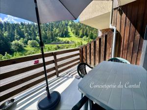 a porch with a table and an umbrella on a balcony at Lioran - Le bonheur de Loustal in Laveissière