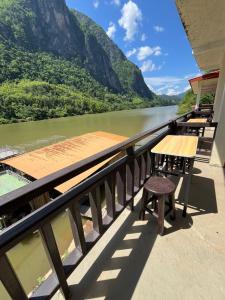 a balcony with tables and chairs overlooking a river at Nongkhaiw Hostel in Nongkhiaw