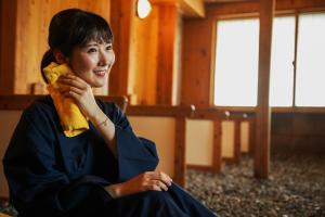 a woman sitting in a room talking on a phone at 六日町温泉 龍氣 in Minami Uonuma