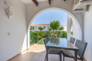 a patio with an archway and a table and chairs at Calma Menorca in Arenal d'en Castell