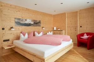 um quarto com uma cama grande e uma cadeira vermelha em Biohotel Walserstuba em Riezlern