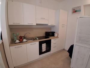 a kitchen with white cabinets and a sink and a microwave at Ca' Dora in Otranto