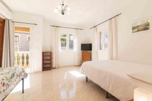 a white bedroom with a bed and a television at Can Cega in Bunyola