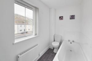 a white bathroom with a toilet and a window at Skinningrove Beach Apartment 5 in Skinningrove +12 photos