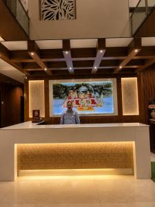 a man standing behind a counter with a projection screen at Hotel Krishna in Katra