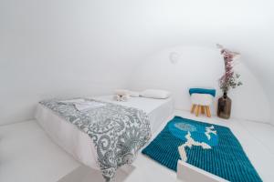 a white room with a bed and a rug at ALMA THERA Boutique Hotel in Perissa
