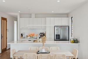 a kitchen with white cabinets and a table with chairs at Snowy Lake Haven in Jindabyne