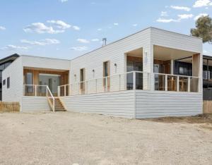 a white house with a balcony on a beach at Snowy Lake Haven in Jindabyne