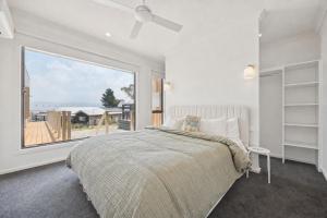 a bedroom with a bed and a large window at Snowy Lake Haven in Jindabyne