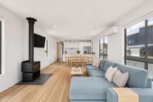 a living room with a blue couch and a stove at Snowy Lake Haven in Jindabyne