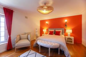 a bedroom with an orange wall and a bed and a chair at Quatorze - manoir au coeur du parc du Château de La Garnache in La Garnache