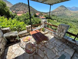 a table and chairs on a patio with mountains in the background at Βαχος rooms 3 in Areopoli