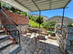 a patio with a table and chairs and mountains at Βαχος rooms 3 in Areopoli +8 photos