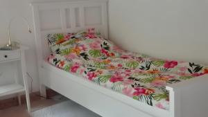 a white bed with a floral bedspread on it at Birkenhof in Achtrup