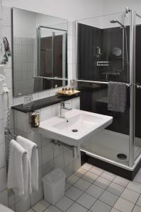 a white bathroom with a sink and a shower at Parkhotel Cloppenburg in Cloppenburg