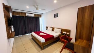 a hotel room with a bed and a television at Peacock residency in Edavanna +5 photos