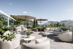 a patio with couches and tables and umbrellas at Small & Beautiful Hotel Gnaid in Tirolo