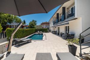 a patio with an umbrella and a swimming pool at CURICTA Design Apartments in Krk