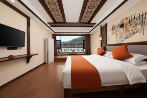 a bedroom with a bed and a flat screen tv at Lissen Hotel -5 min to Forest Park East Gate & Tour Tickets-Butler-recommended travel routes in Zhangjiajie