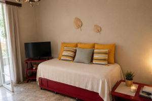 a bedroom with a bed with pillows and a television at Nostalgia by the Sea in Agioi Theodoroi