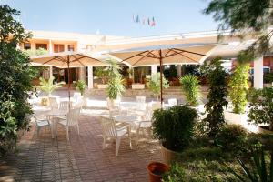 
a patio area with tables, chairs and umbrellas at Hotel Avenida in Benicàssim
