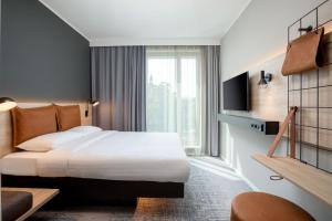 a hotel room with a bed and a large window at Moxy Dortmund City in Dortmund