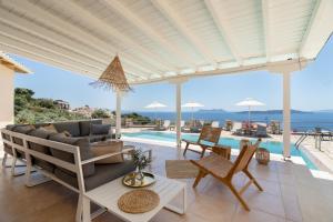 a patio with a couch and chairs and a pool at Villa Olivia Panoramic Sea View in Lefkada