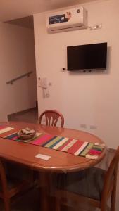a wooden table with two chairs and a television on the wall at Quintana Duplex in Junín