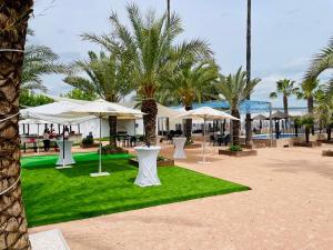 a resort with tables and umbrellas and palm trees at Hacienda Guadalquivir in Córdoba