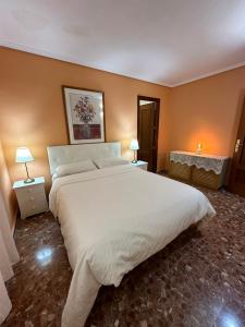 a bedroom with a large white bed and two lamps at piso en puerto de Jávea in Jávea