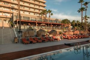 a hotel with chairs and a pool in front of a building at Caramelo Calvia Beach - Adults Only in Magaluf