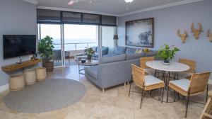 a living room with a couch and a table and chairs at 404 Oyster Rock - by Stay in Umhlanga in Durban
