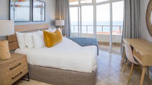 a bedroom with a bed with a desk and a view of the ocean at 404 Oyster Rock - by Stay in Umhlanga in Durban +33 photos