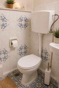 a white toilet in a bathroom with blue and white tiles at Nostalgia by the Sea in Agioi Theodoroi