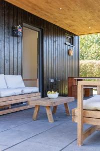 a patio with a bench and a bowl of fruit on a table at De Goudbalpeer - Ruim en luxe vakantiehuis voor 6 personen met uitzicht op wijngaard in Ruinerwold +5 photos