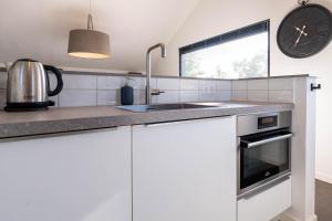 a kitchen with white cabinets and a sink and a clock at De Goudbalpeer - Ruim en luxe vakantiehuis voor 6 personen met uitzicht op wijngaard in Ruinerwold