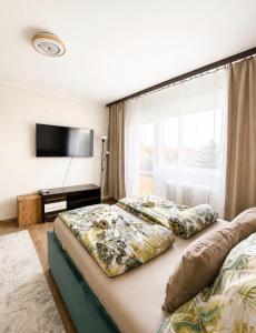 a bedroom with two beds and a flat screen tv at Tófenék Deluxe Apartman in Szolnok