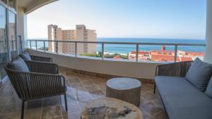a balcony with a couch and chairs and a view of the ocean at 404 Oyster Rock - by Stay in Umhlanga in Durban