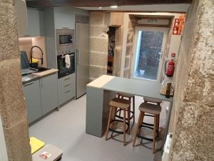 a kitchen with a island and two stools at Loureiros Dorm in Santiago de Compostela