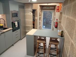 a kitchen with a counter and two bar stools at Loureiros Dorm in Santiago de Compostela +54 photos