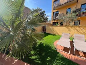 two chairs and a palm tree next to a building at Ground floor apartment in Centre of Torroella De Montgri in Torroella de Montgrí