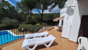 a patio with two white chairs and a swimming pool at TV 57 privat pool in Torroella de Montgrí