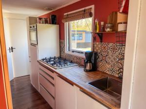 a kitchen with red walls and a white refrigerator at Chalet Siësta in Anloo - Next to the forest in Anloo