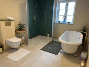 a bathroom with a tub and a toilet and a sink at Boots and Bikes B&B in Neksø