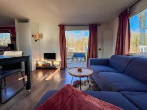 a living room with a blue couch and a table at Chalet Siësta in Anloo - Next to the forest in Anloo