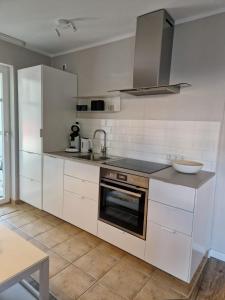 a kitchen with white cabinets and a sink at FeWo Gisa - Graal Müritz in Graal-Müritz +9 photos