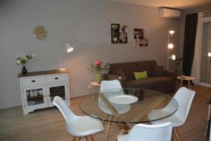 sala de estar con mesa de cristal y sillas blancas en Apartamento Flavia II Sant Damià, en Sitges