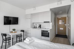 a white kitchen with a bed and a table at Hiisi Homes Turku Fleminginkatu in Turku