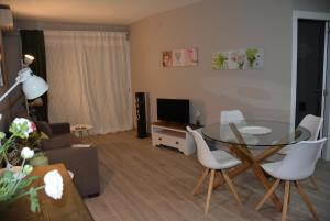 - un salon avec une table en verre et des chaises blanches dans l'établissement Apartamento Flavia II Sant Damià, à Sitges